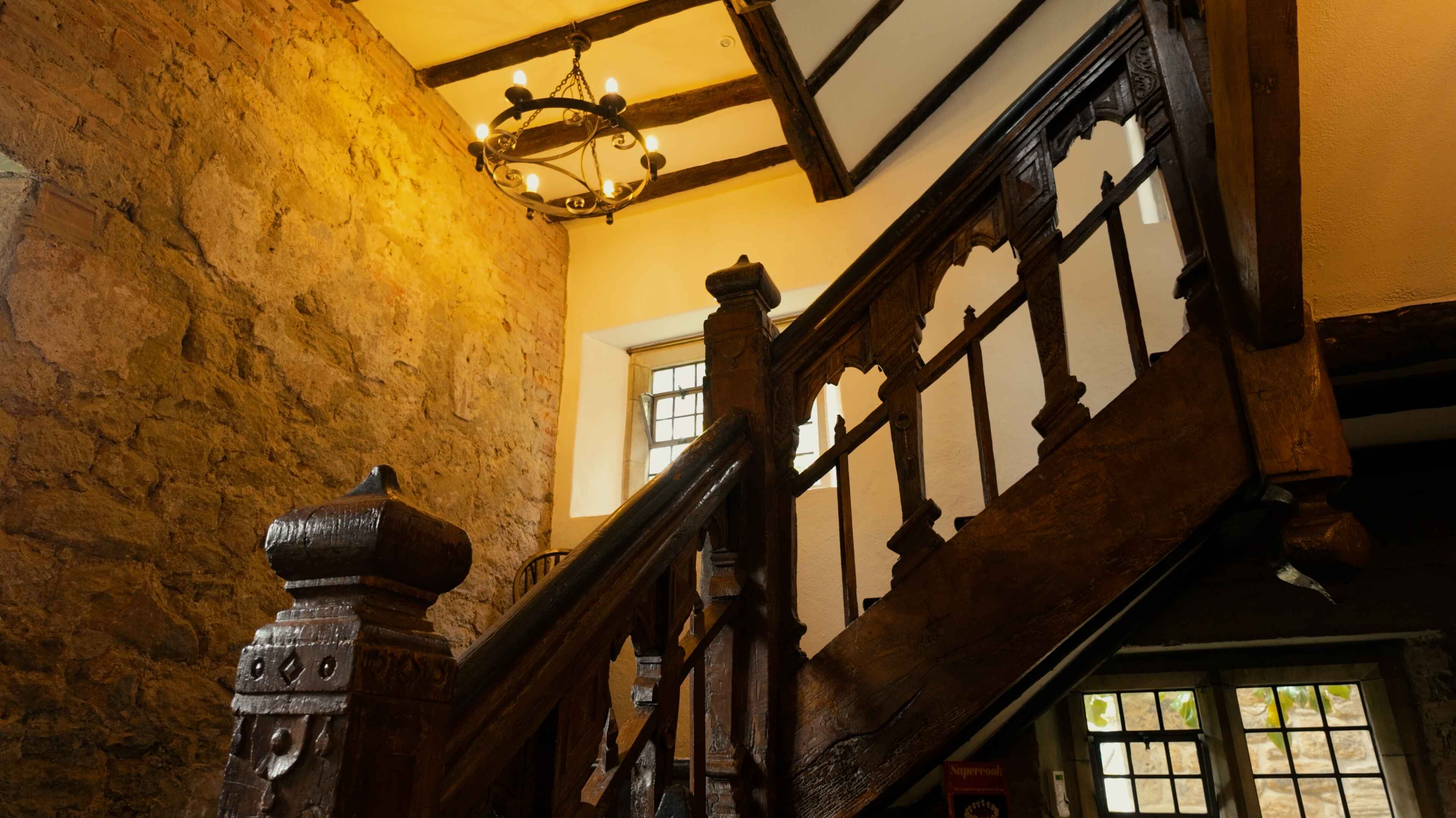Interior view of a stone building featuring wooden stairs leading to an upper level