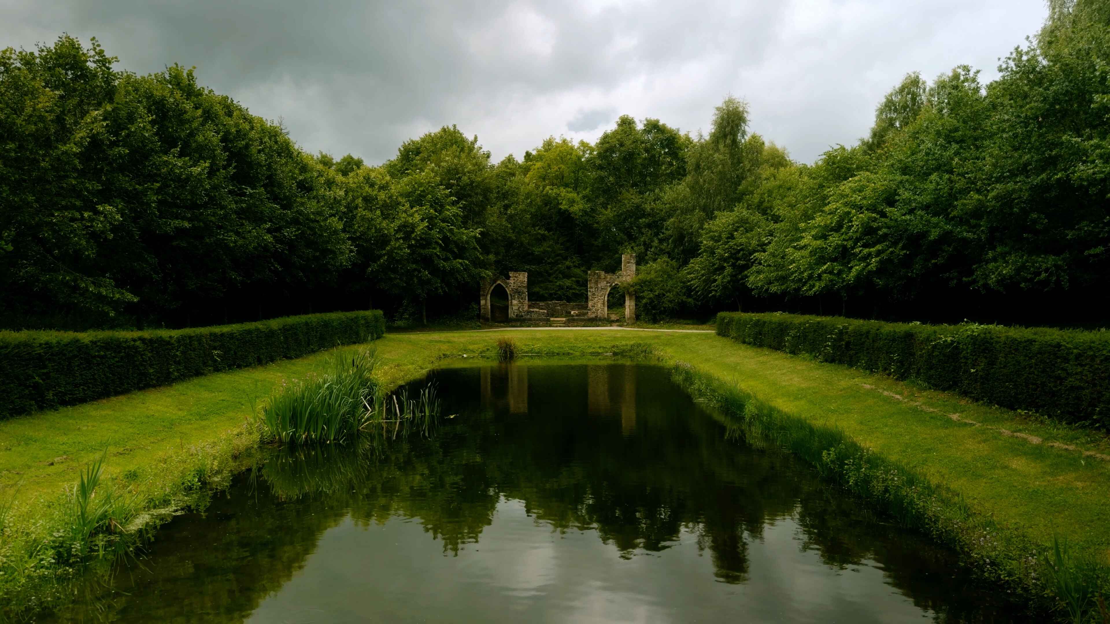 Old ruins in the backdrop with a large stretch of water and lush foliage bordering it