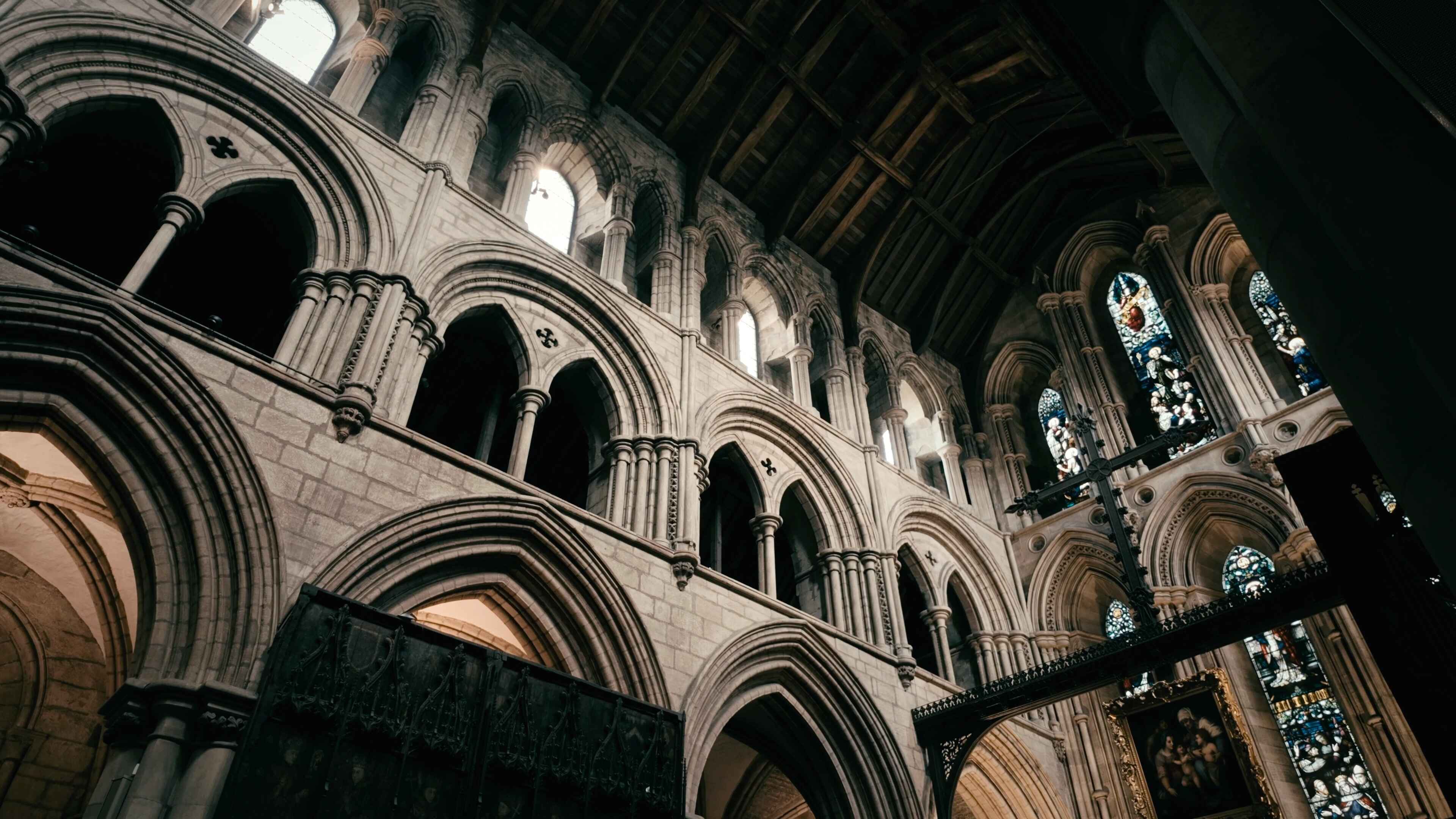 Several windows and archways of an abbey with light pouring in from outside