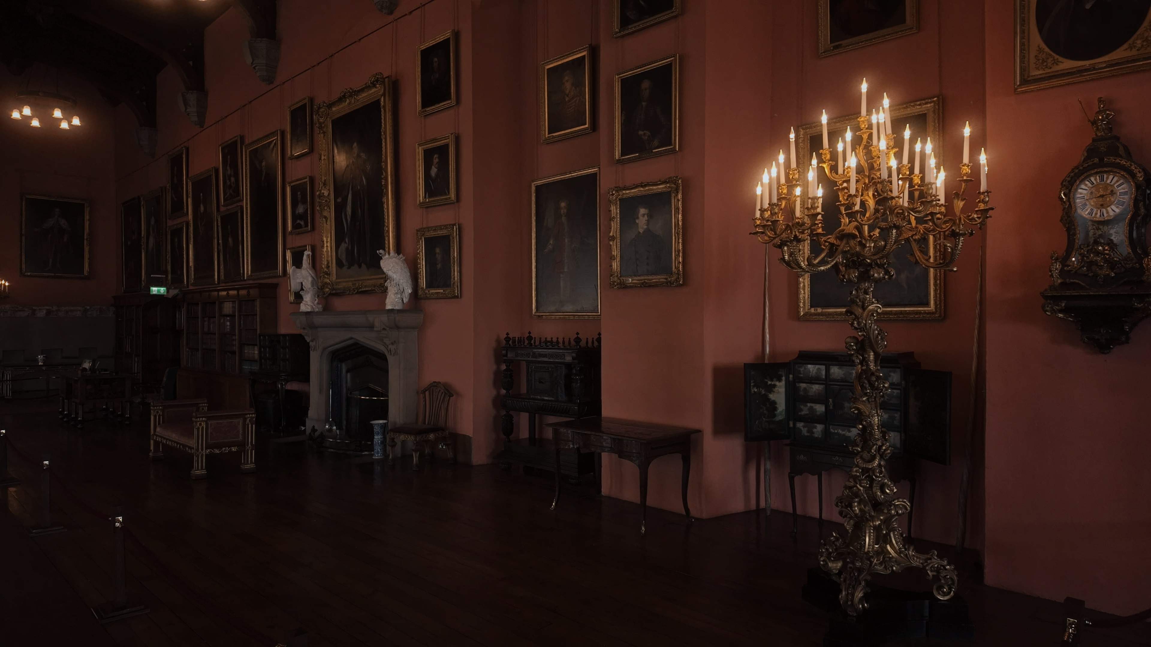 A large room with several paintings along the wall and a floor-standing candelabrum