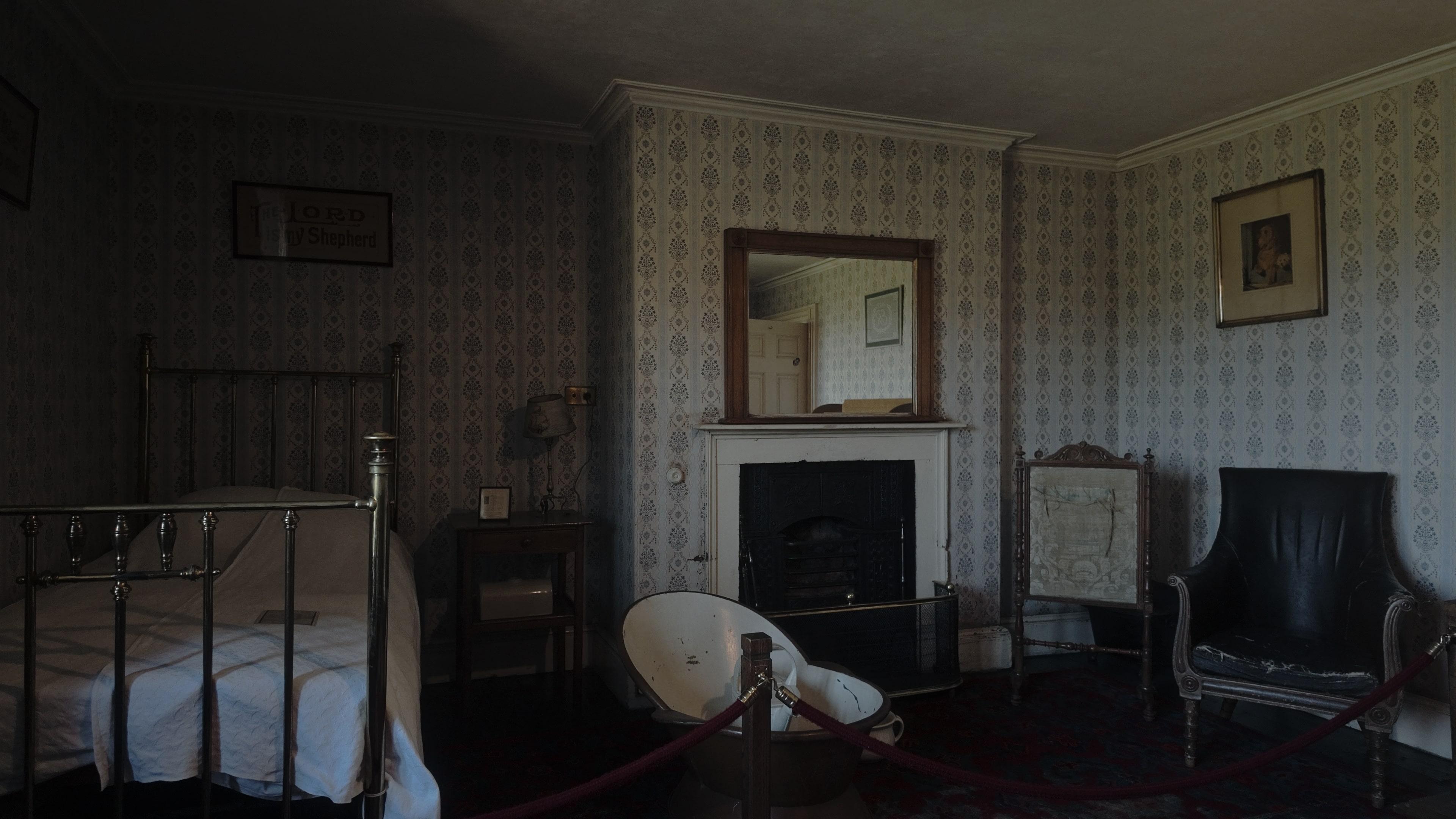 An 18th Century bedroom with a bed, bath, coal fireplace and mirror