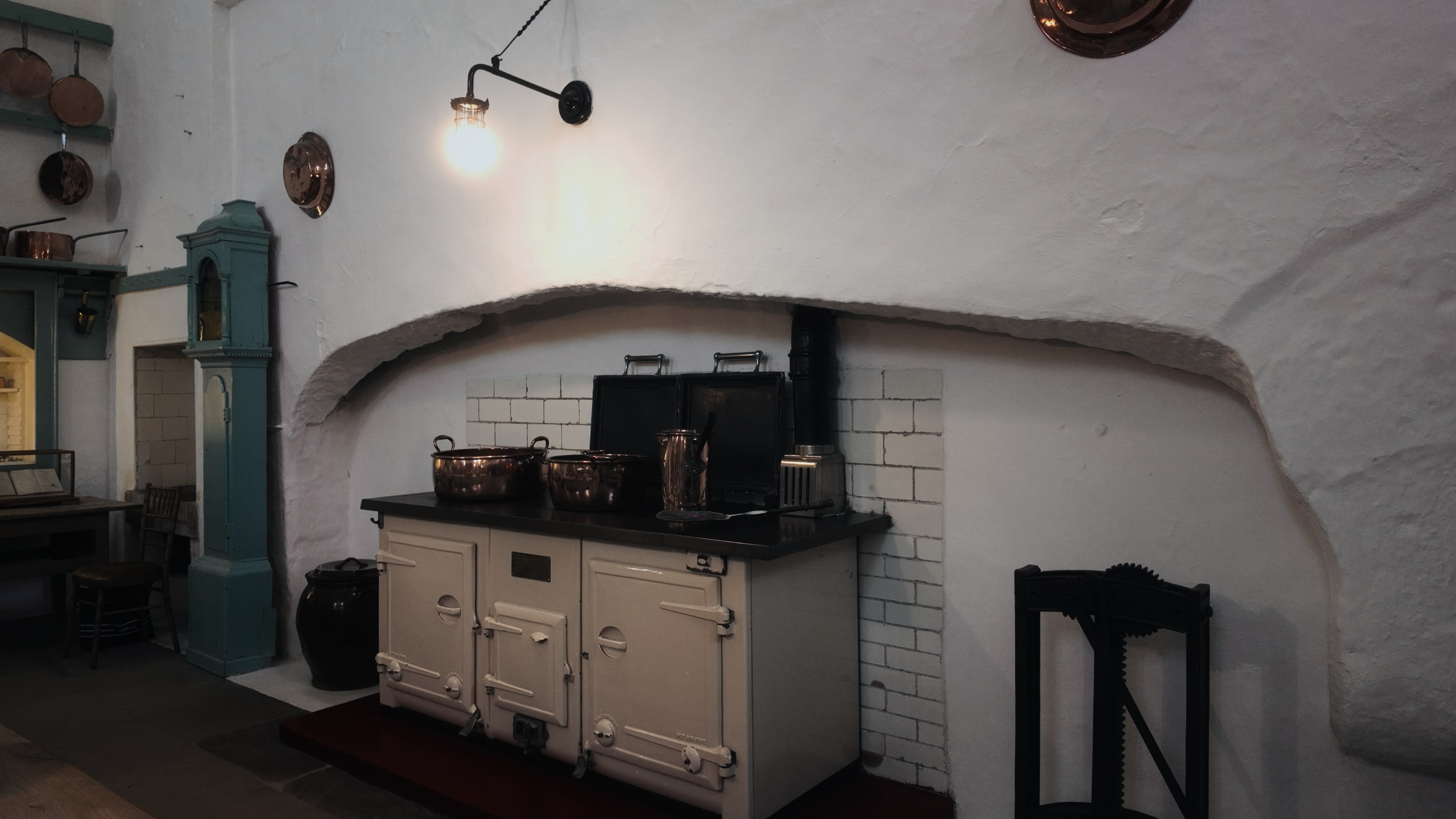 An old stove in a kitchen with various metal pots and pans