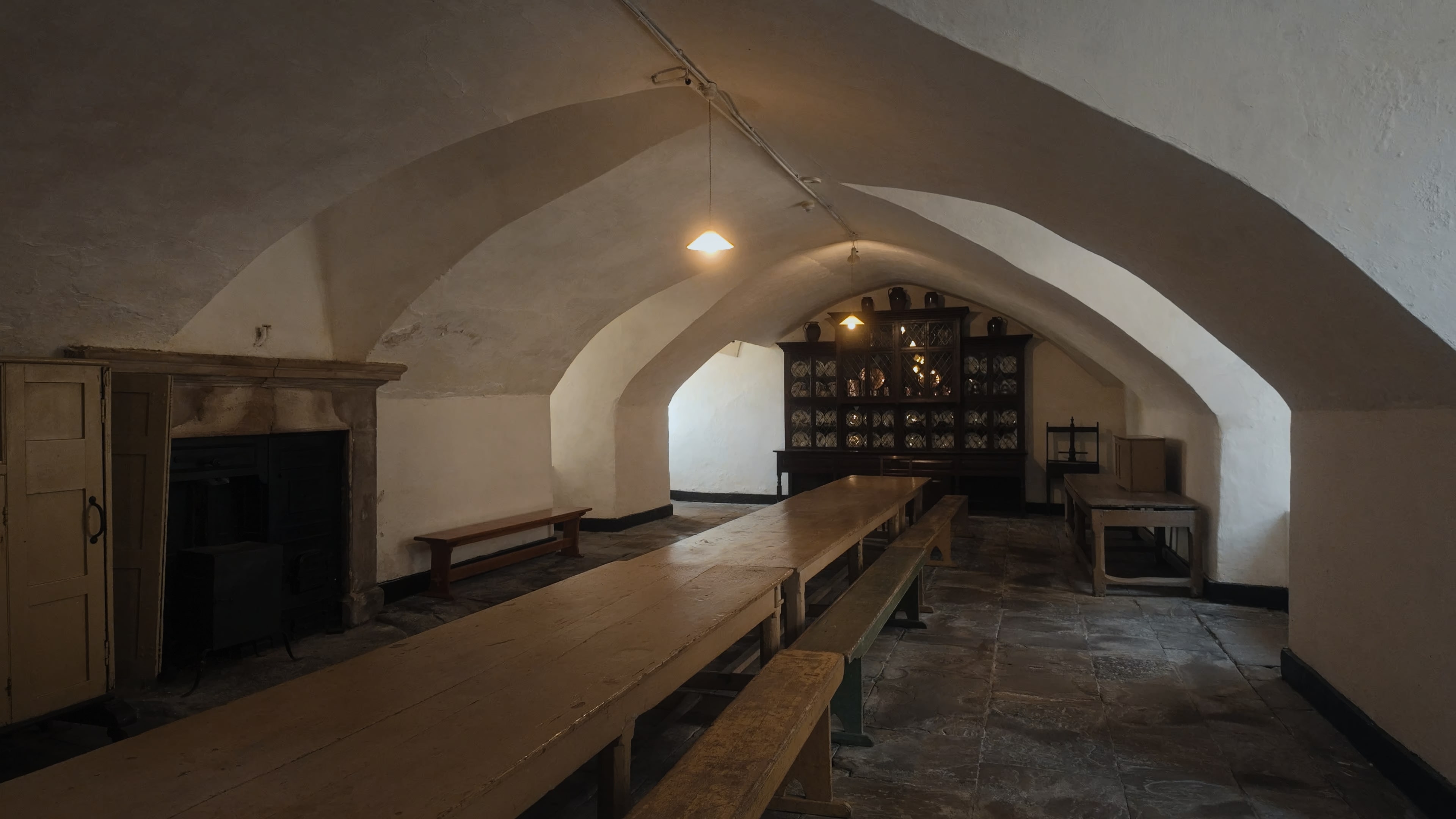 An old dining room with a long stretch of table and a cabinet of crockery at the back