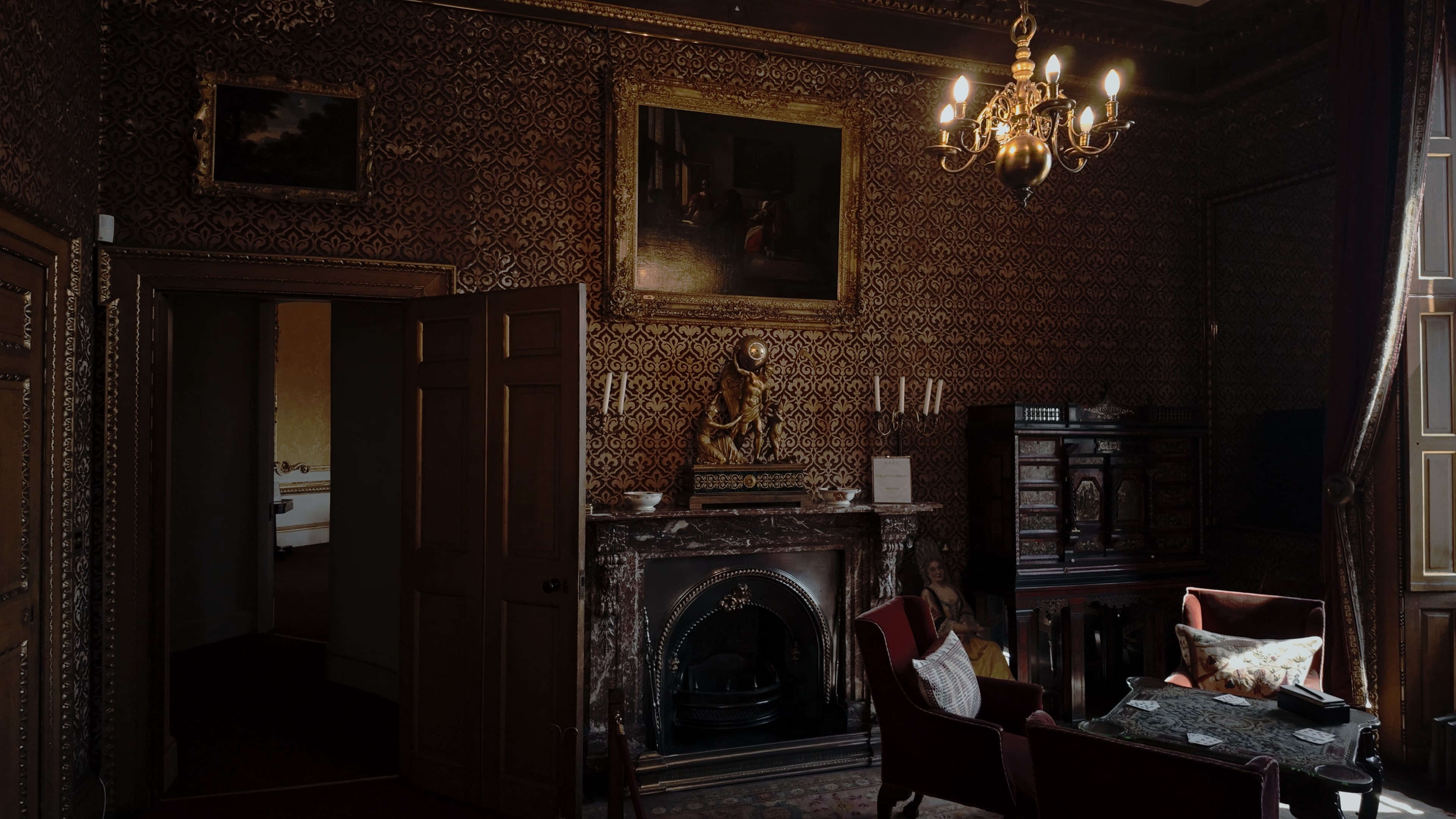 A room with a fireplace, various statues and paintings