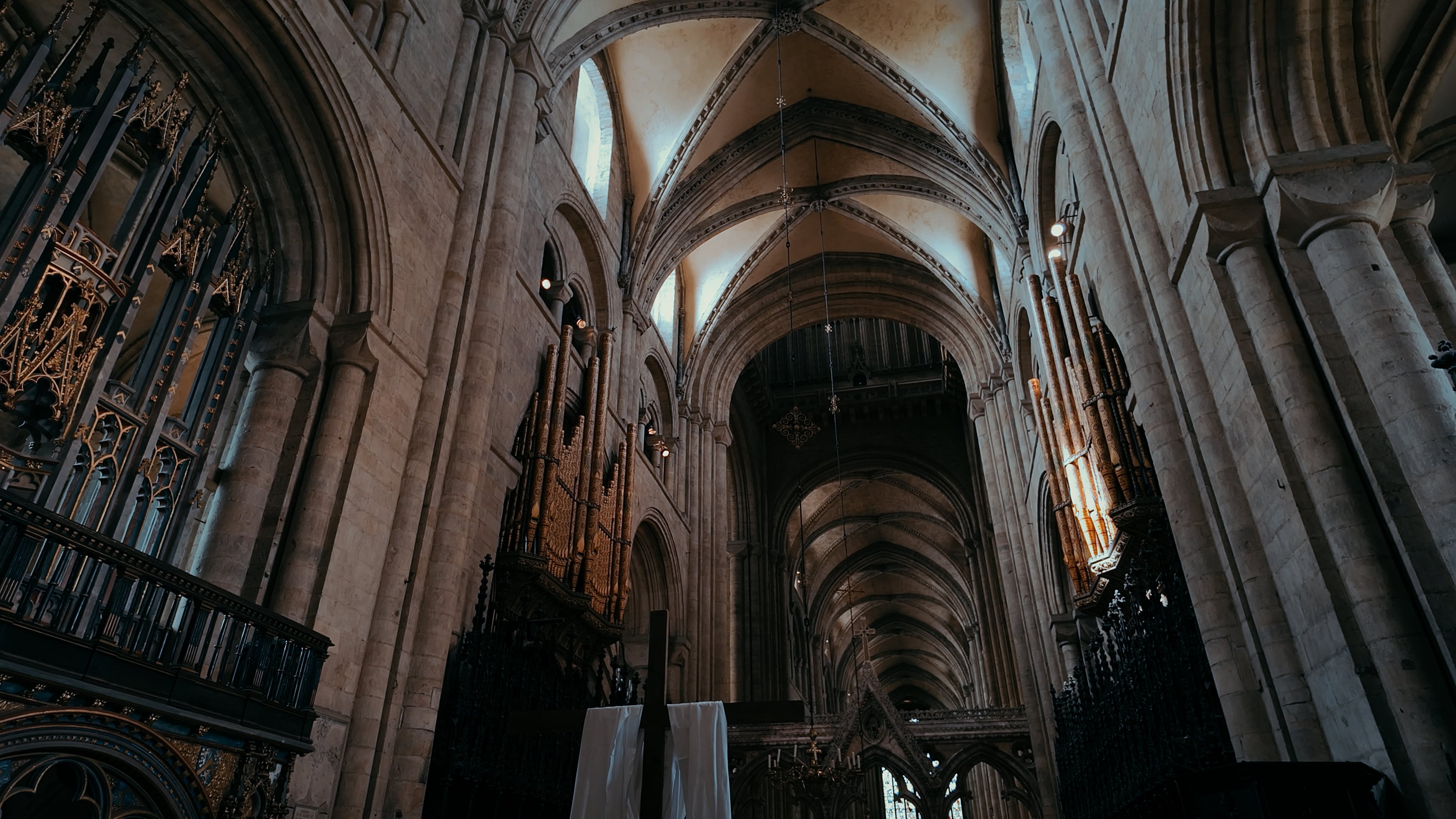 Organ pipes along the walls of a cathedral with ornate engravings and archways