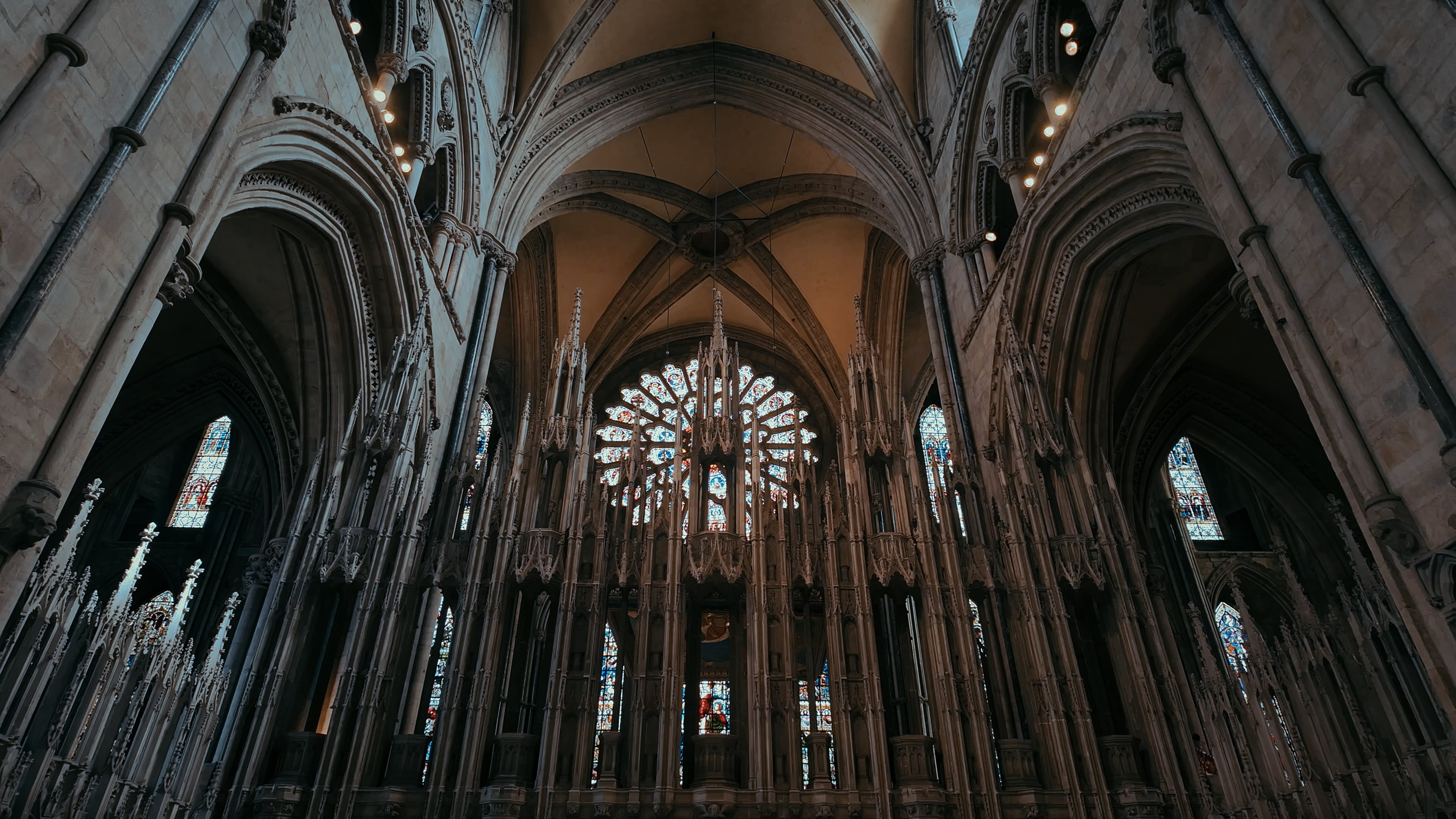 Church spires between hallways and a large circular stained glass window in the backdrop