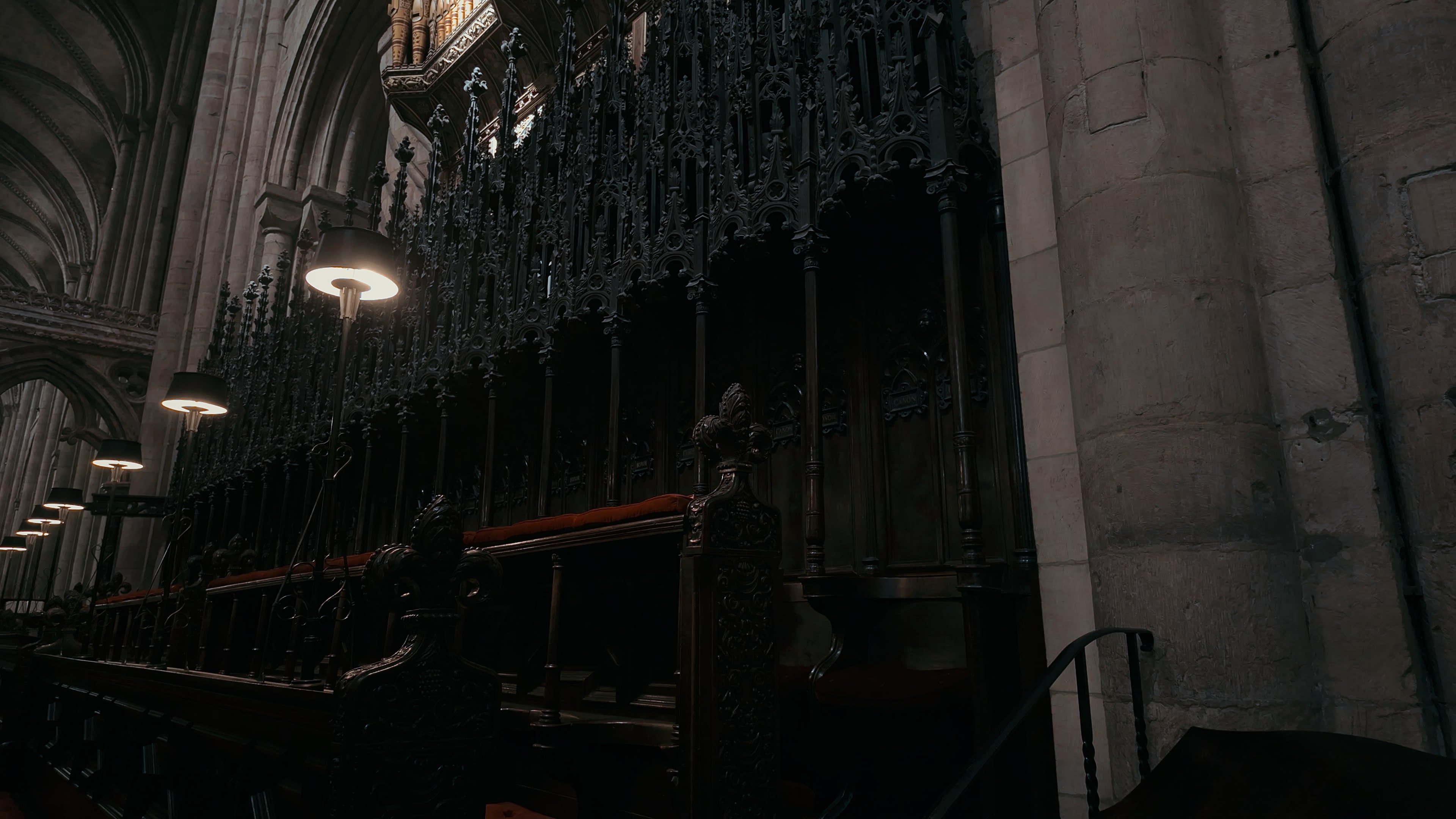 Church choir pews adorned with red velvet lining and shaded lights overhead