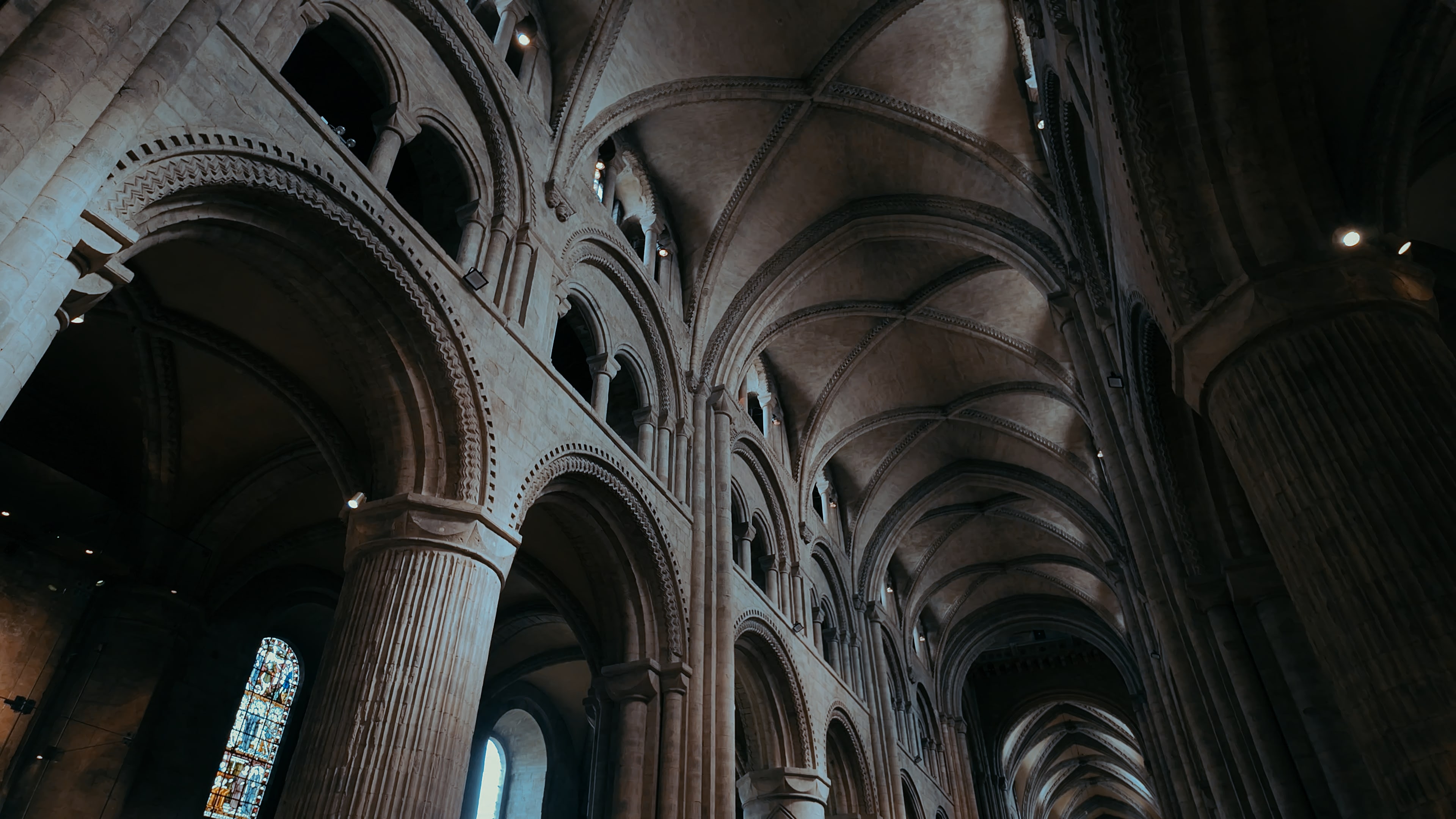 A long cathedral hallway with pillars and curved stone archways