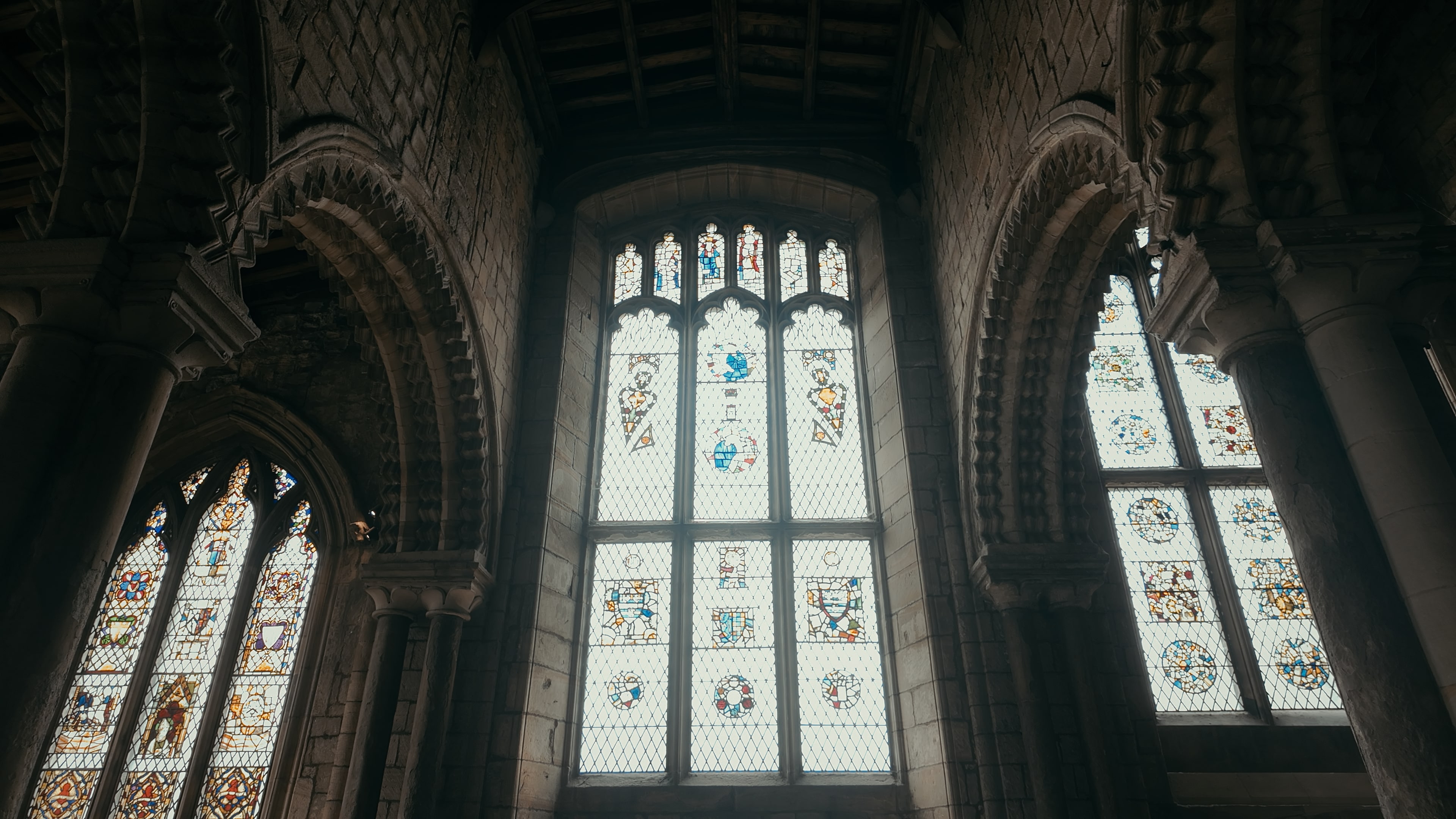 A series of stained glass windows with a crested hallway either side