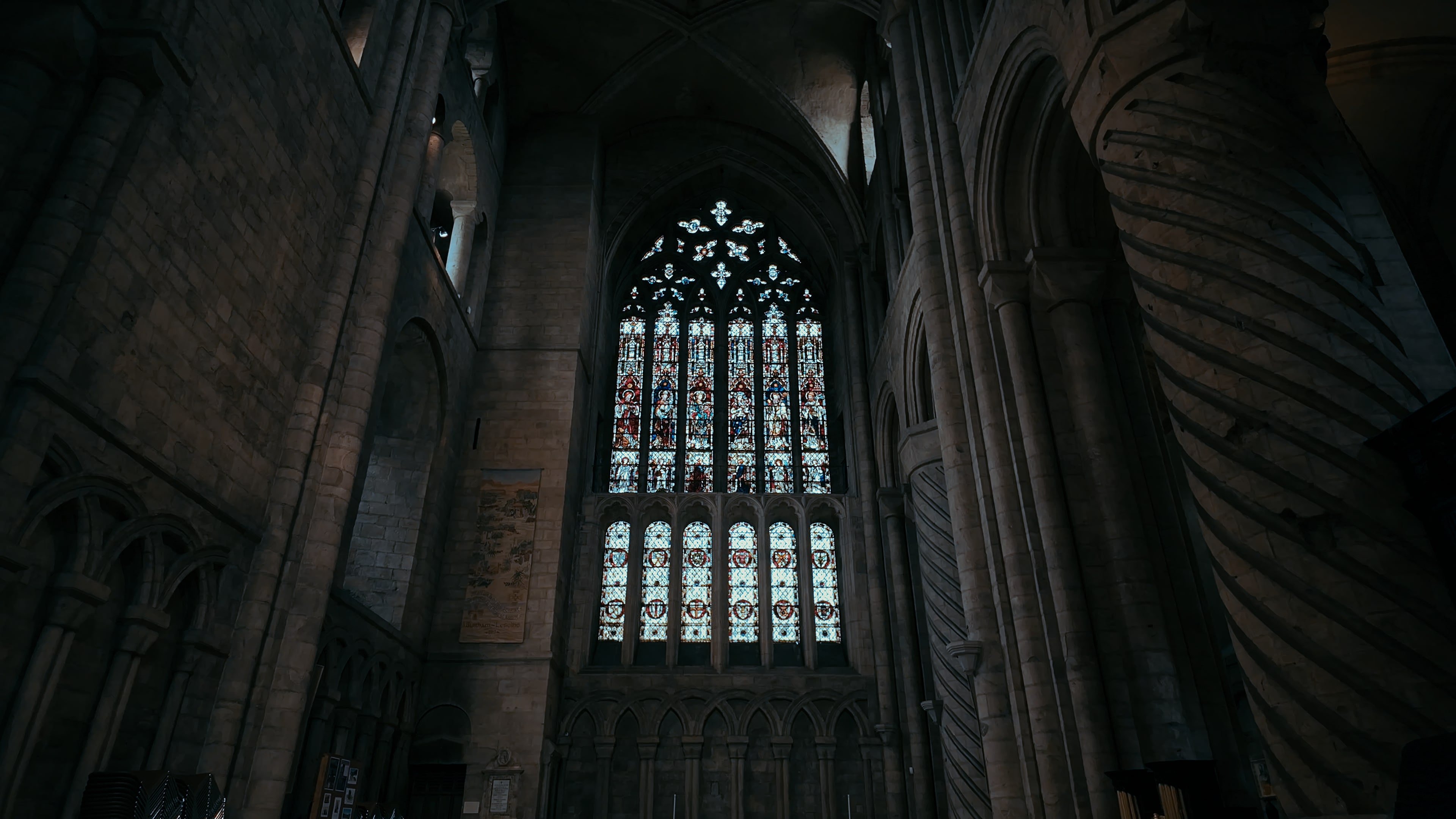 A large stained glass window between two crested stone archways