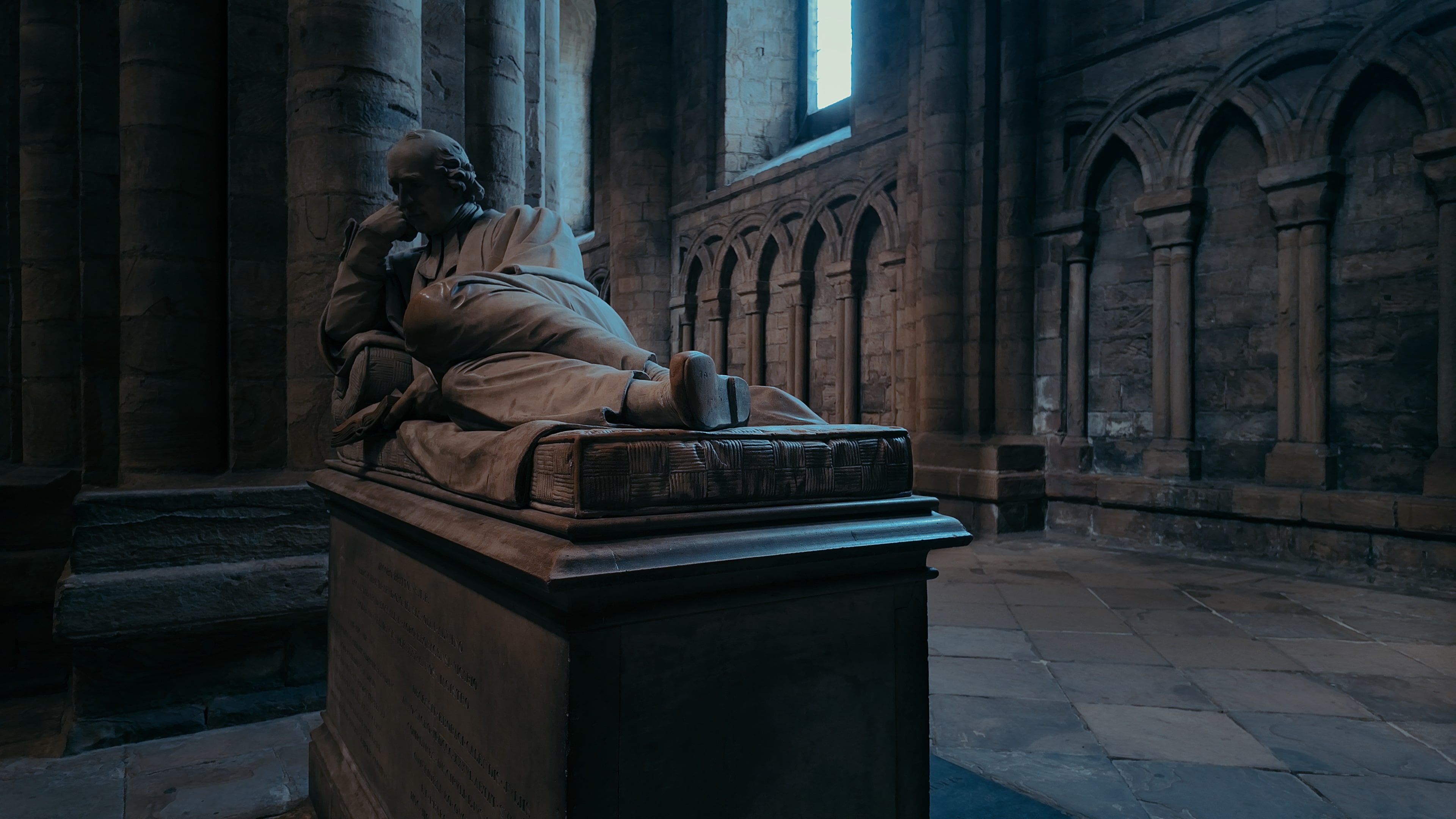 A tomb with a statue of a man lying sideways resting on top