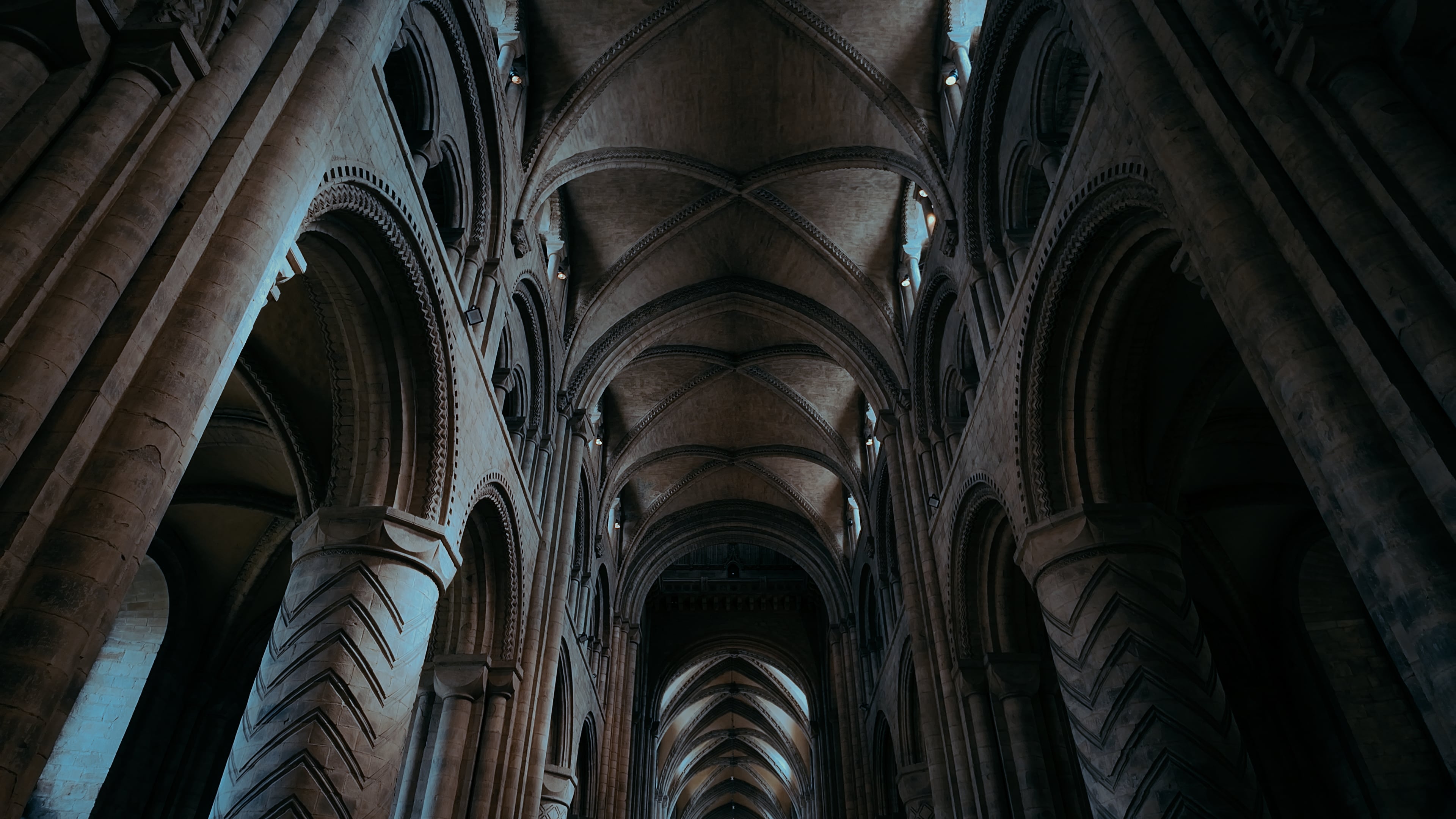 A large, long cathedral hallway with pillars and curved archways along both sides