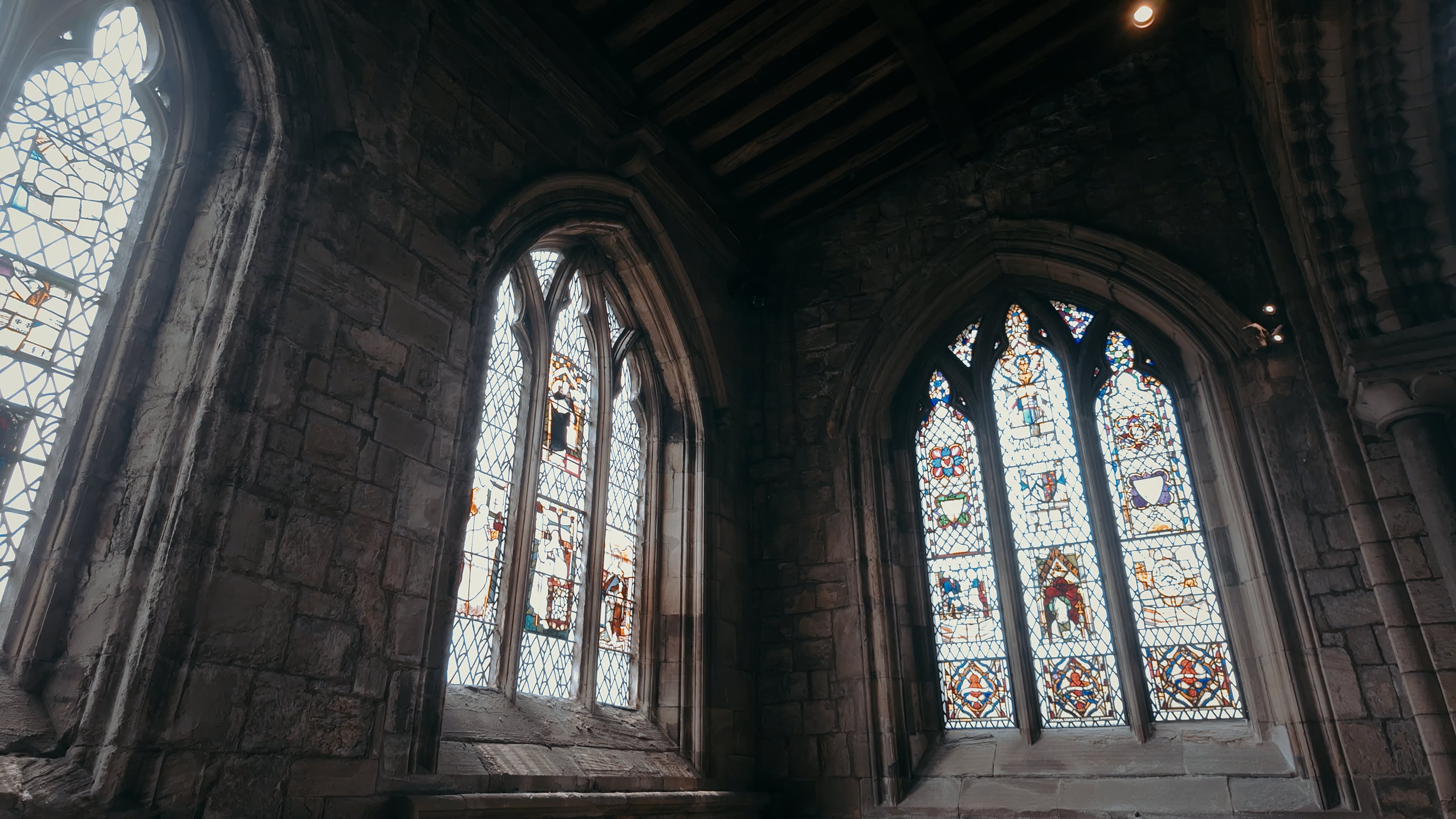 Two stained glass windows joined at the intersect of a corner with light pouring in