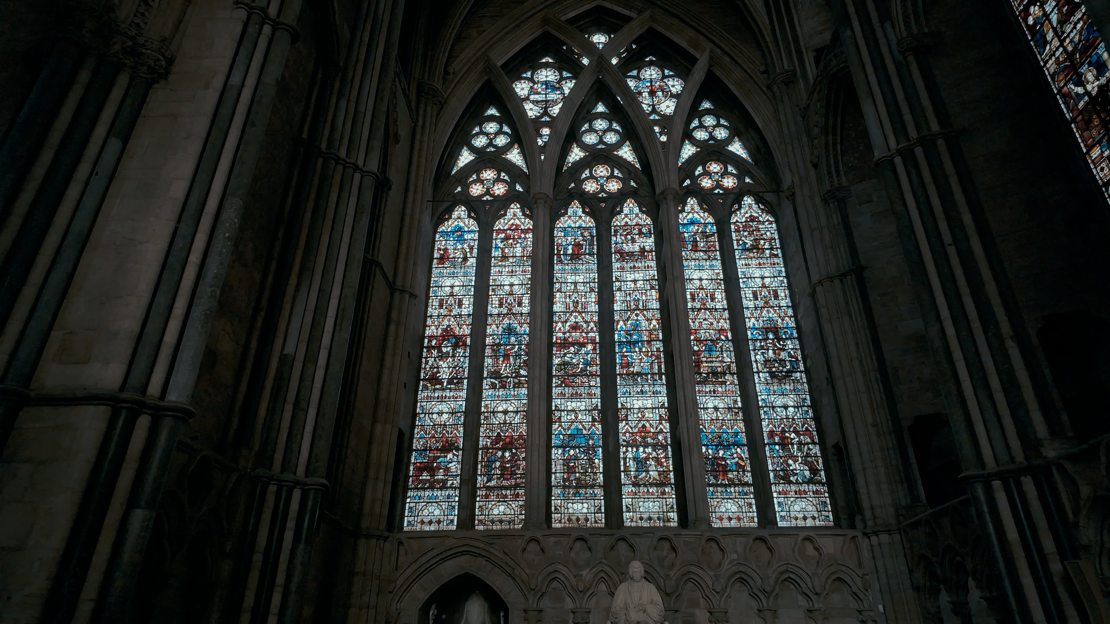 A large stained glass window with a sculpture in front