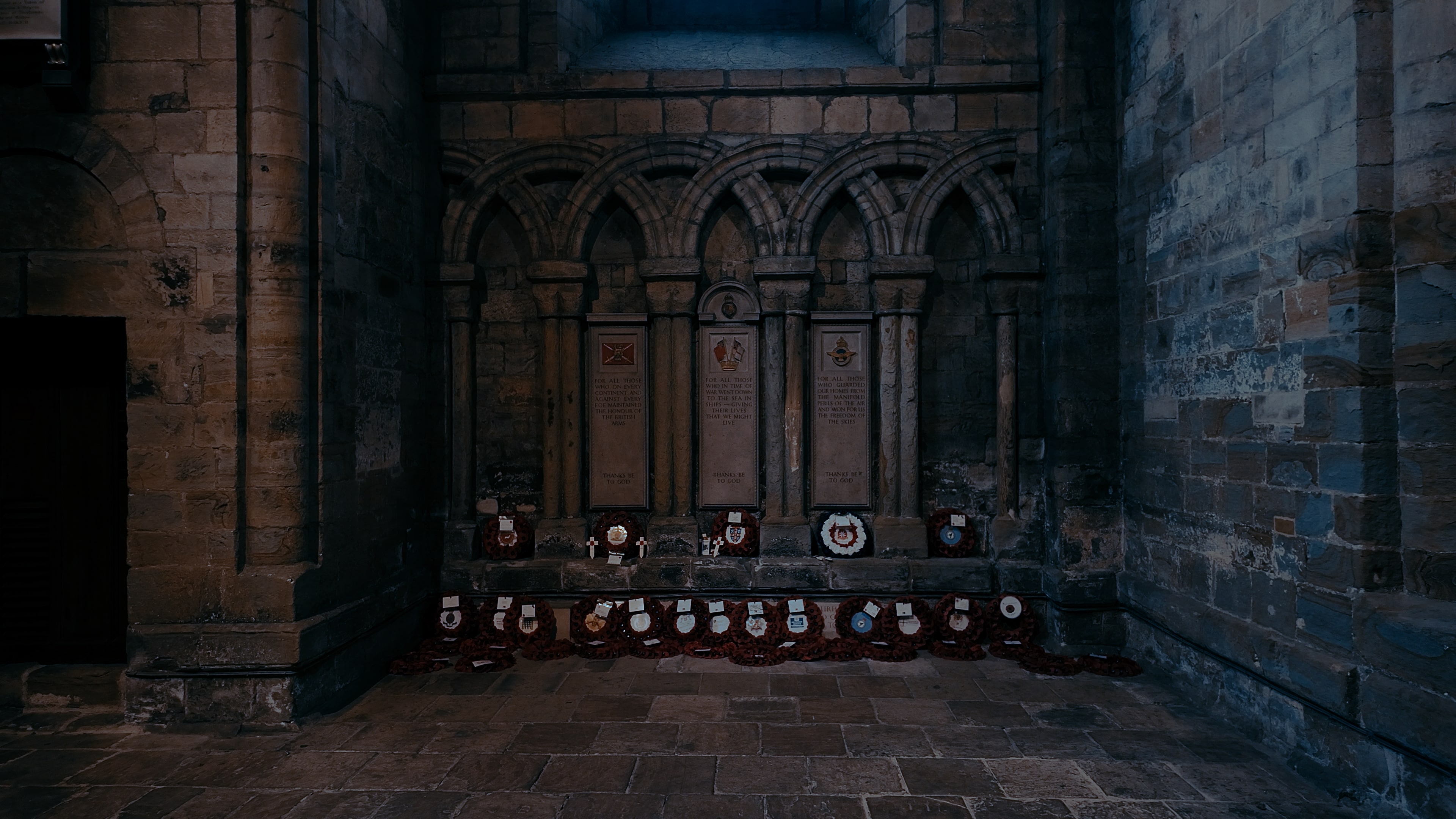 A memorial wall with poppy wreaths dotted alongside the floor