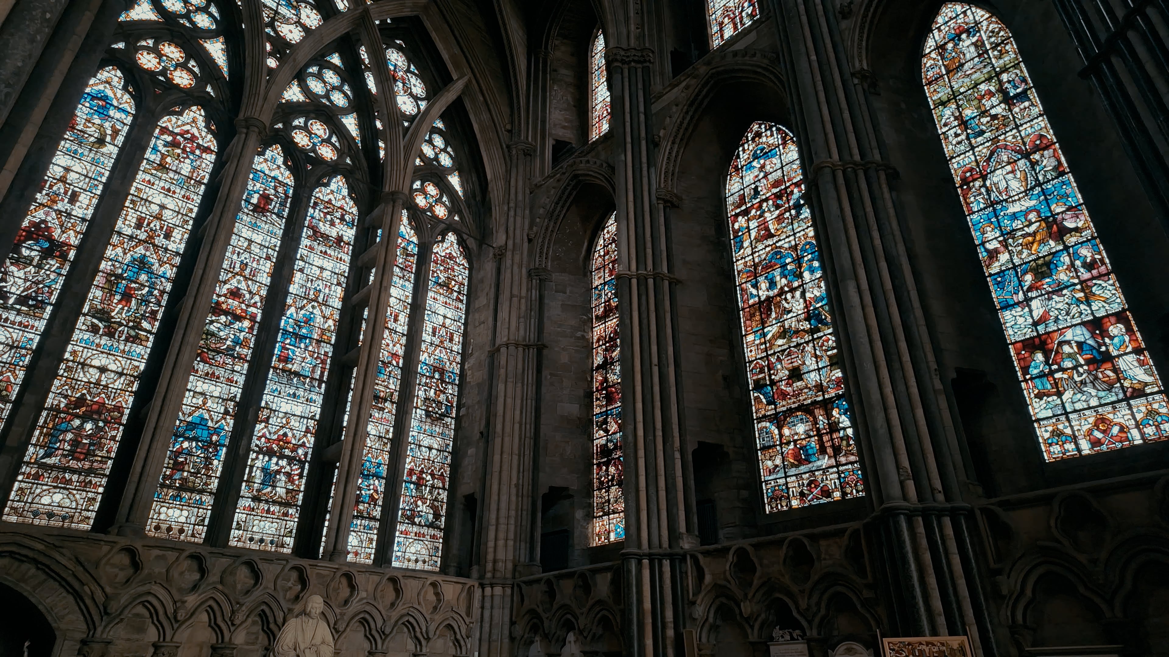 Large stained glass windows intersecting at a corner of a cathedral