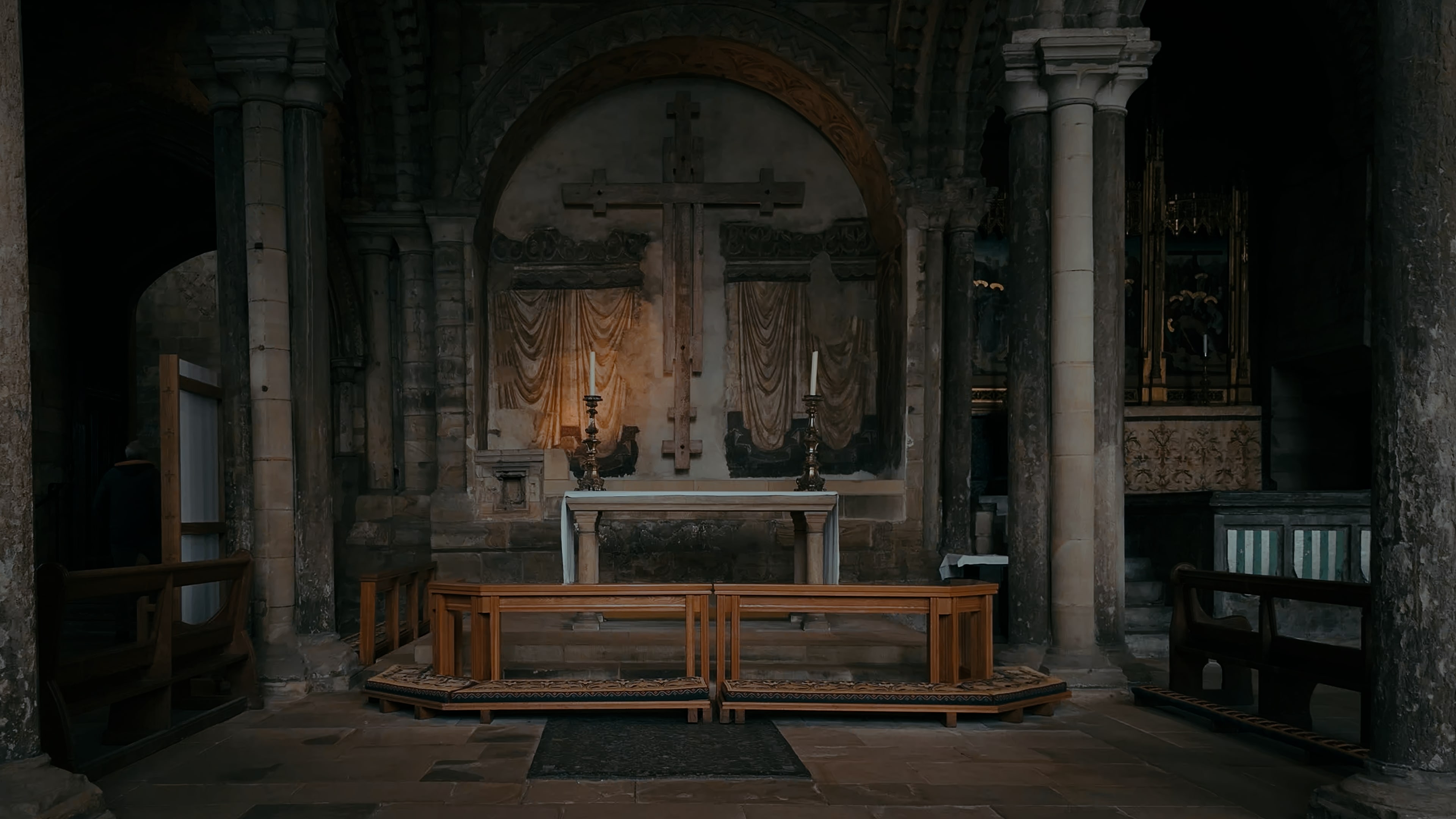 A shrine with a wall-mounted cross and two candles in front
