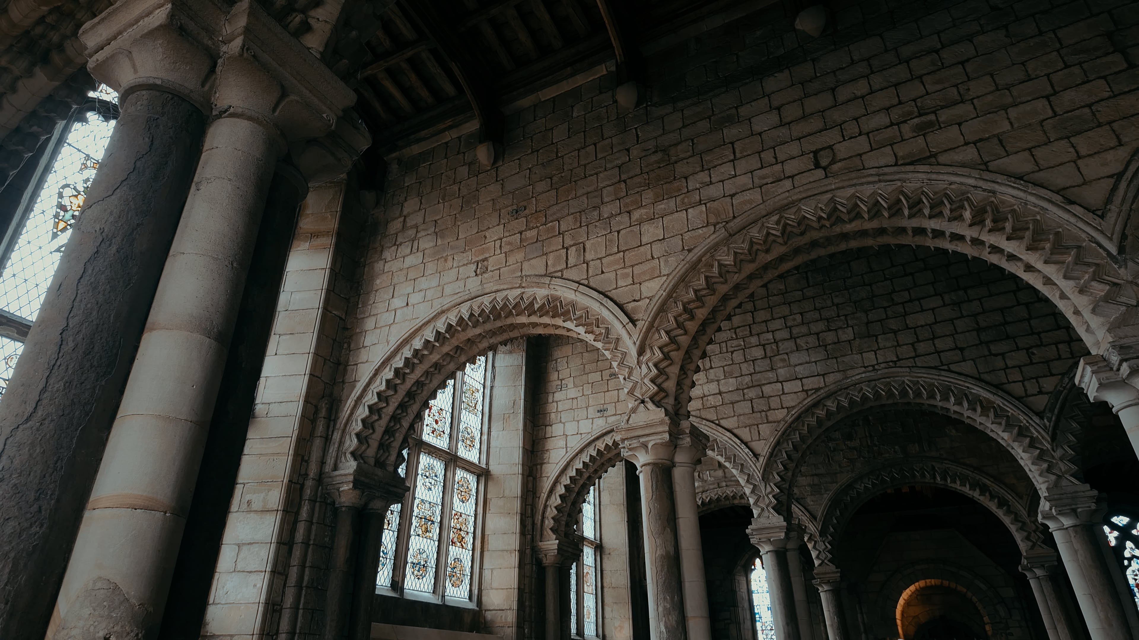 A series of crested stone archways and stained glass windows on the left